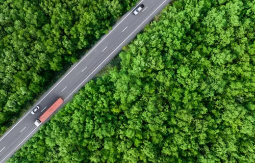 aerial view of a car and truck driving on highway road through a forest