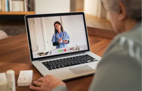 Elderly patient video conferences doctor on laptop