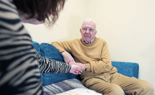 An older man listening to a female social care worker